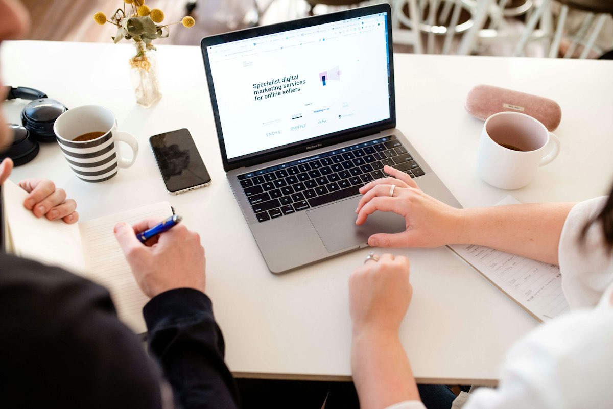 Table de travail avec ordinateur portable, carnet et tasses de café pendant la préparation d'un projet