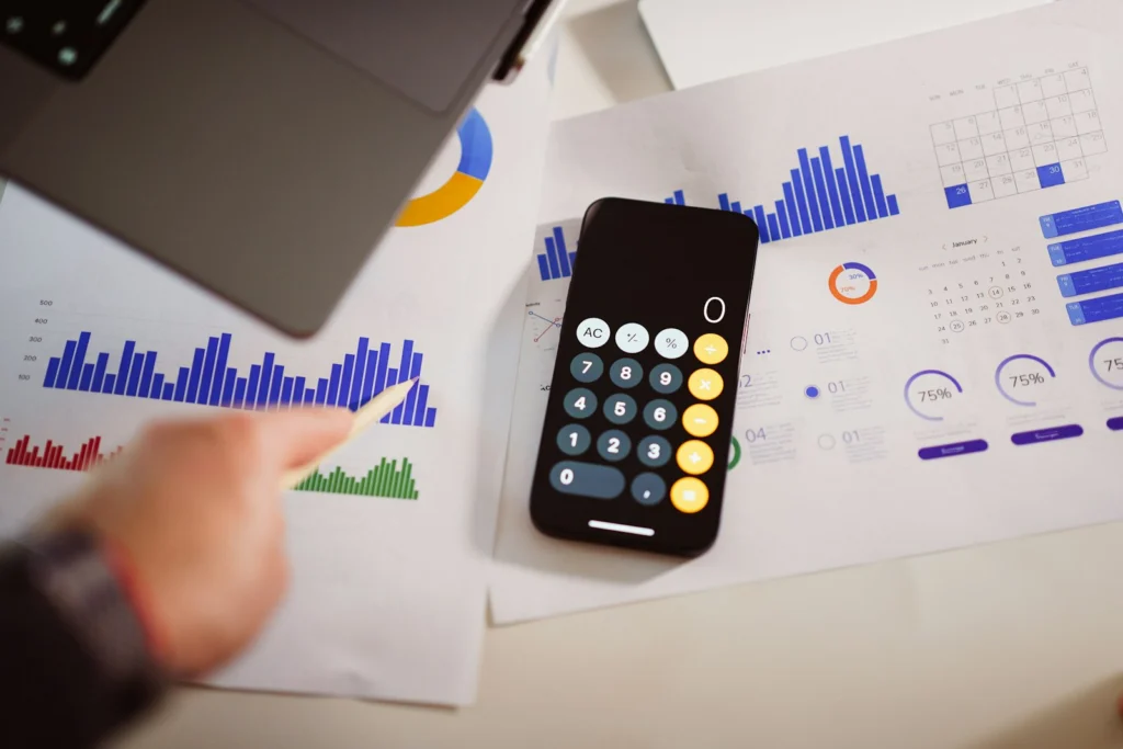 Calculatrice posée à côté d'un ordinateur portable pour estimer le budget d'un projet d'intelligence artificielle