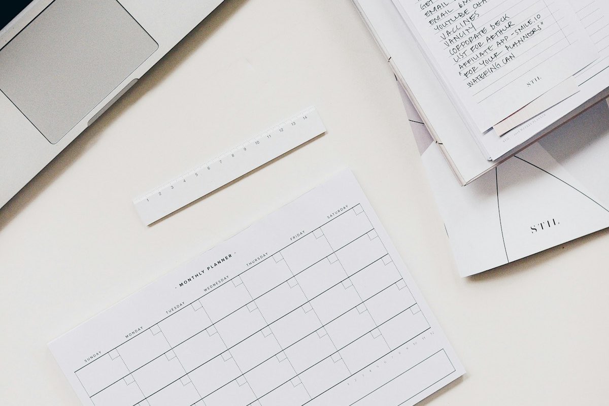Planning mensuel papier posé sur un bureau clair à côté d'un ordinateur portable